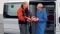 Deux installateurs professionnels du génie climatique discutent d'un projet de partenariat devant un camion de service Viessmann.
