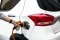 L'image montre une voiture électrique en train d'être rechargée par l'intermédiaire d'une boîte murale domestique.