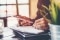 Une femme tient un smartphone et saisit des notes dans un bloc-notes.