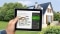 Tablette avec le calculateur dédié à la rénovation ; en arrière-plan : Maisons individuelles