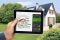 Tablette avec le calculateur dédié à la rénovation ; en arrière-plan : Maisons individuelles